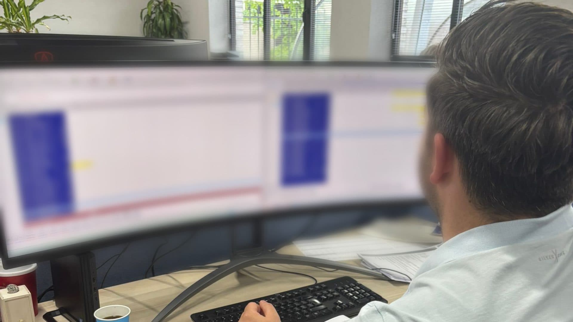 Medewerker van een afbouwbedrijf werkt met projectbeheersoftware op een breed beeldscherm