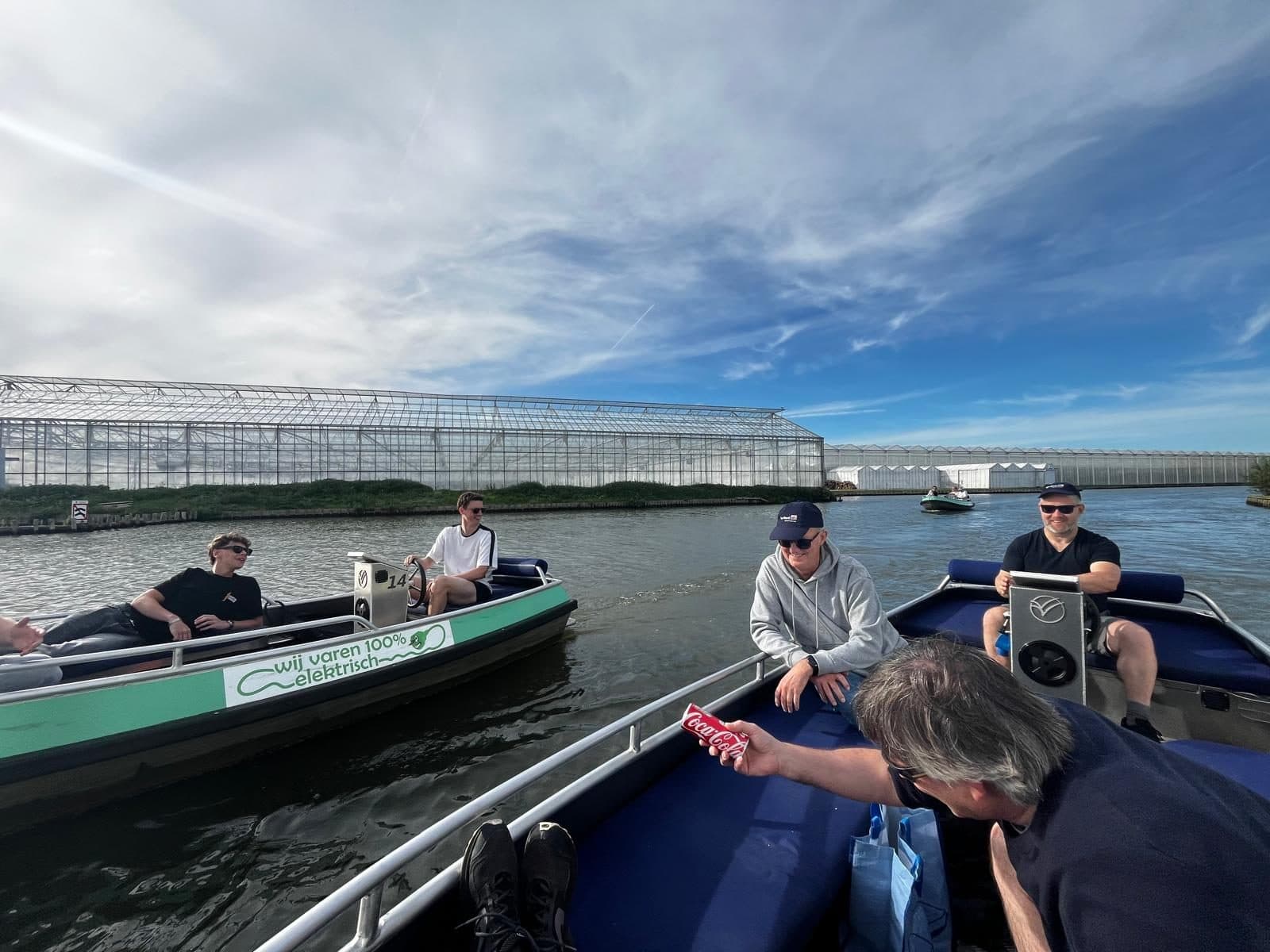 Drie elektrische huurbootjes met collega's van MSG software op het water bij De Zweth, met kassen op de achtergrond
